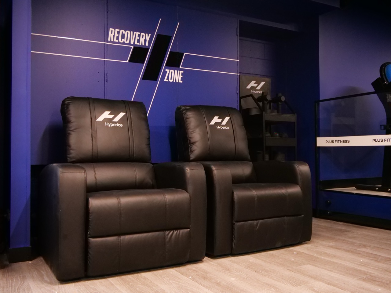 Recovery zone — Hyperice massage chairs with branded blue wall
